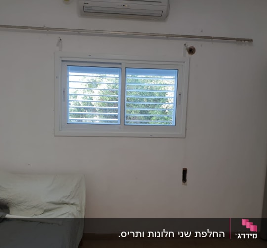 חלון עם תריסי אלומיניום על קיר לבן